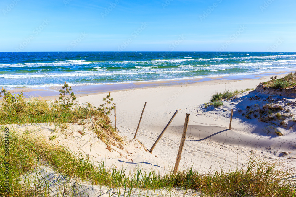 Entrance to beautiful white sand beach with blue sea near Kolobrzeg, Baltic Sea coast, Poland