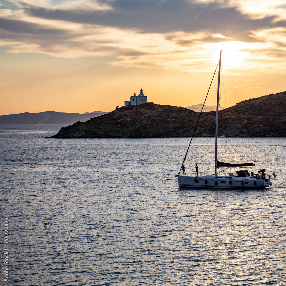 Fototapeta premium Sailing at sunset, Mediterranean sea. Lighthouse at Kea island, Greece.