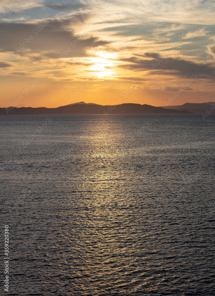 Sunrise, sunset clouds. Twilight, dusk cloudy sky over sea water, mountain silhouette