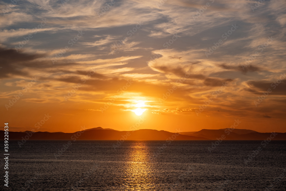 Sunrise, sunset clouds. Twilight, dusk cloudy sky over sea water, mountain silhouette Sunrise, sunset clouds. Twilight, dusk cloudy sky over sea water, mountain silhouette