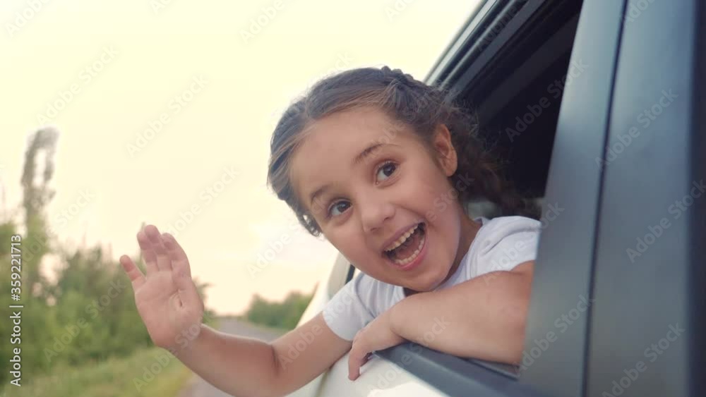 happy girl kid child smile leaned out of a car window waving hand. happy family travel journey lifestyle concept. daughter sister looks out of a car window. little happiness girl drive road to happy girl kid child smile leaned out of a car window waving hand. happy family travel journey lifestyle concept. daughter sister looks out of a car window. little happiness girl drive road to