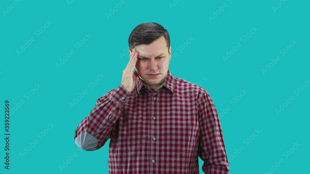 A man dressed in a plaid shirt holds his head in his hand from a headache. A man dressed in a plaid shirt holds his head in his hand from a headache.
