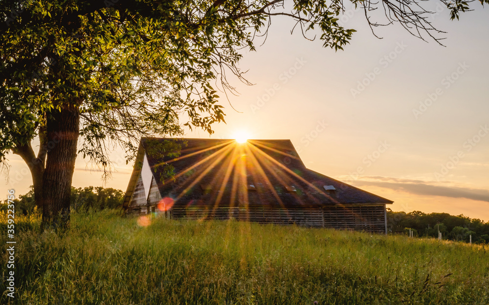 An old abandoned barn under sunset with sunburst, sunstars