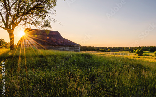 An old  abandoned barn under sunset with sunburst, sunstars