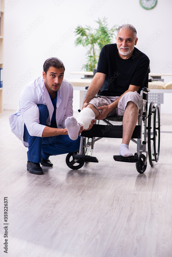 Old injured man visiting young male doctor traumatologist Old injured man visiting young male doctor traumatologist