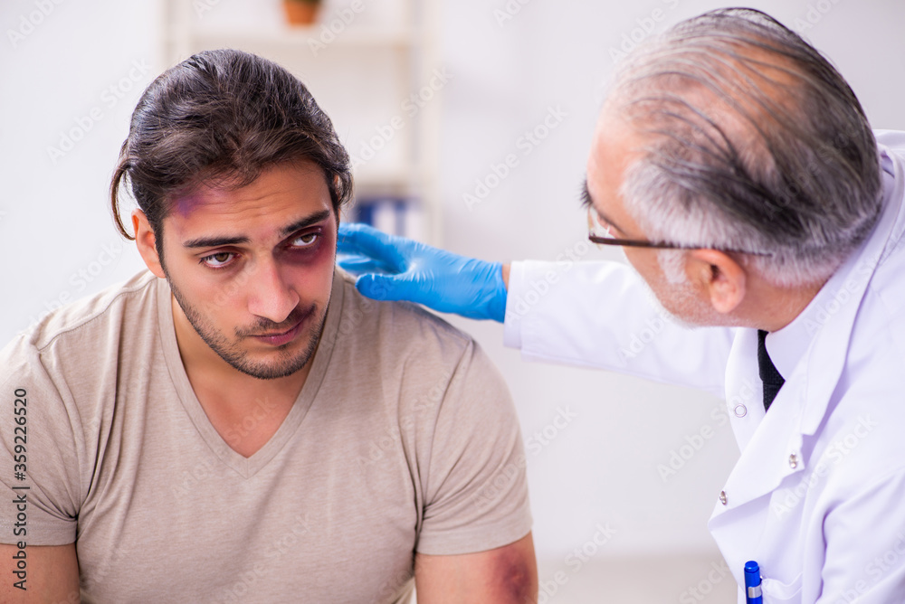 Fototapeta premium Young face injured man visiting experienced male doctor traumato