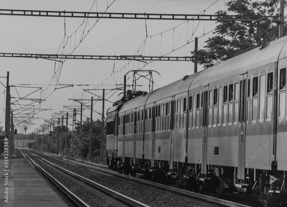 Black and white view of lectric blue engine and coaches on fast railway