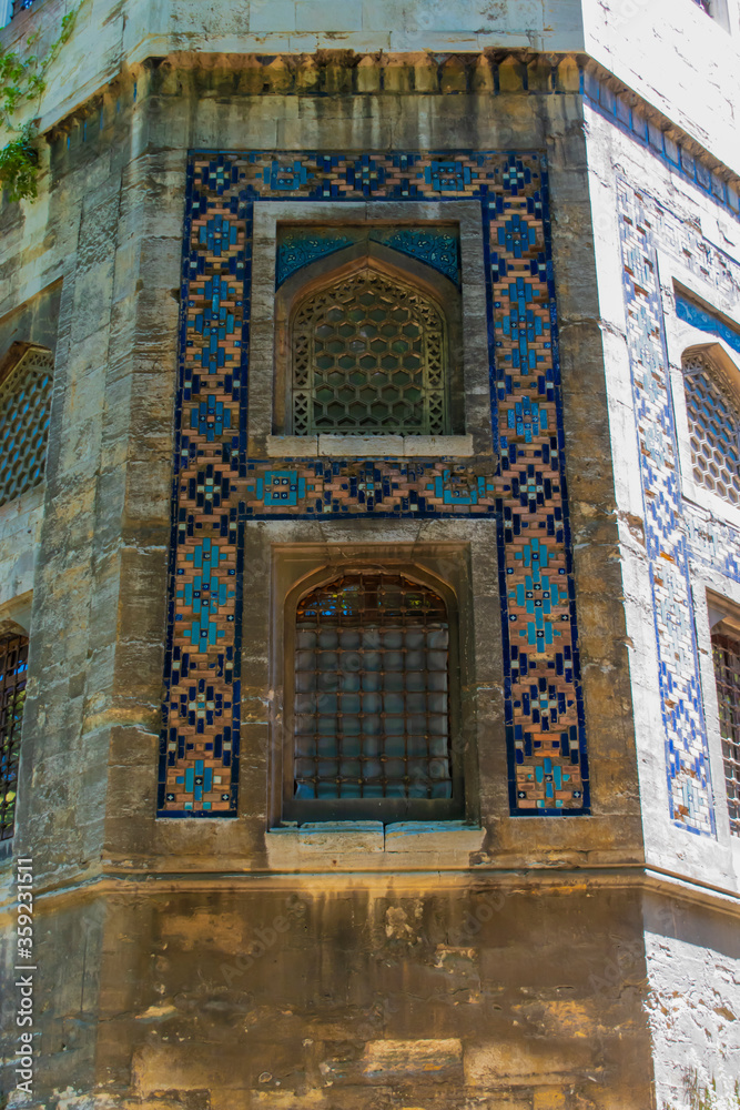 Large historic building covered with tiles. building with large windows and decorated with colorful motifs around it. Historic building with old worn ornaments.