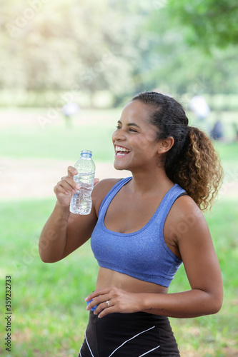 Obraz na płótnie Portrait of a 20-30 year old woman wearing gym clothes drinking water After jogging in the park w salonie
