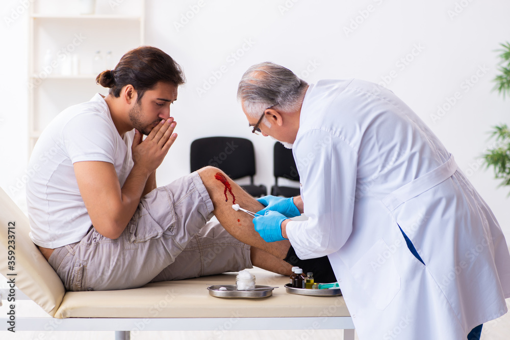 Fototapeta premium Leg injured man visiting old doctor in first aid concept