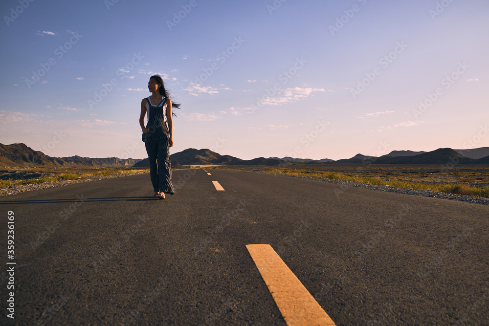 Asian girl walking along the road in between mountains.