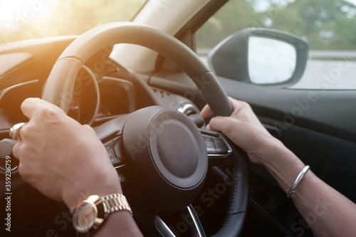 hands of car driver on steering wheel, driving on the empty road, travel background. Car steering wheel. © suriyapong