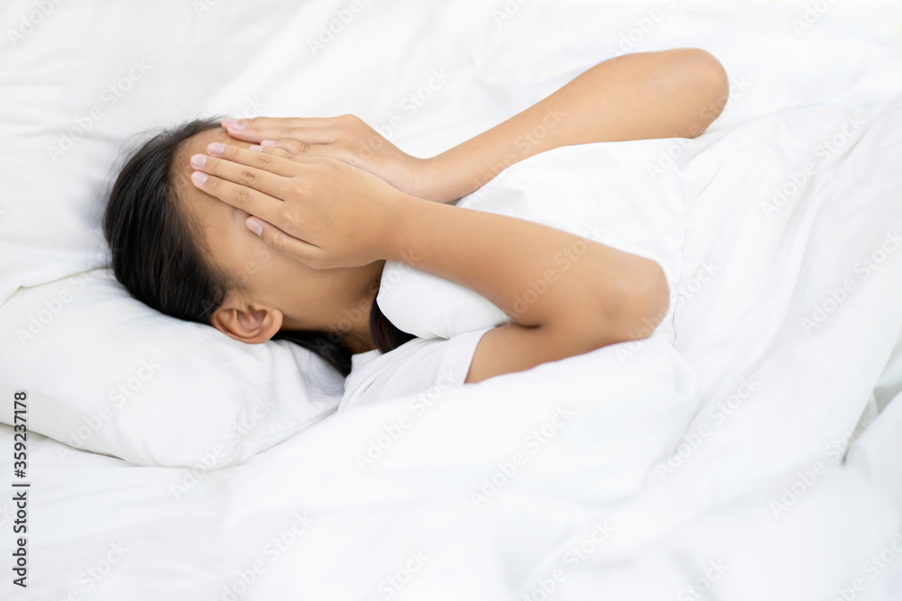 Young beautiful child girl sad expression covering face with hands while crying on the white bedroom. Depression concept.Copy space background. Young beautiful child girl sad expression covering face with hands while crying on the white bedroom. Depression concept.Copy space background.