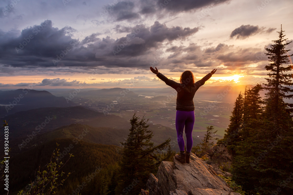 Adventurous Girl on top of a Rocky Mountain overlooking the beautiful Canadian Nature Landscape during a dramatic Sunset. Taken in Chilliwack, East of Vancouver, British Columbia, Canada.