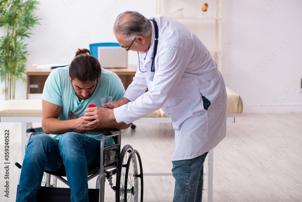 Experienced doctor and young male patient in wheel-chair