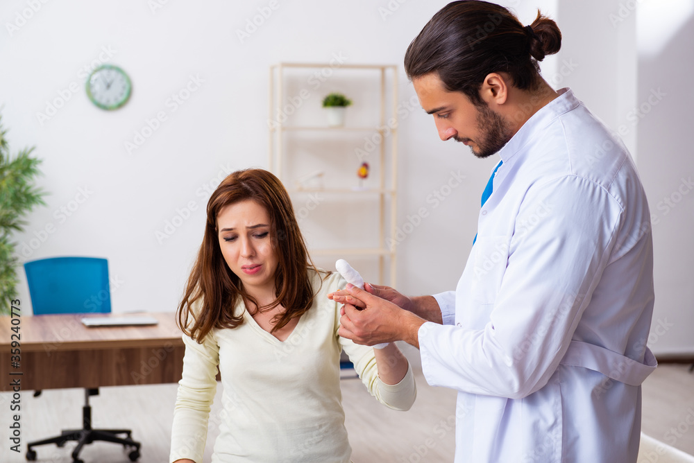 Fototapeta premium Young hand injured woman visiting male doctor traumatologist
