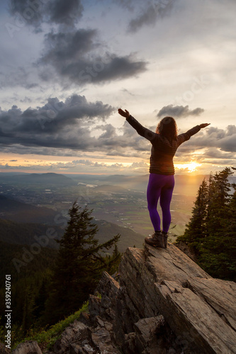 Adventurous Girl on top of a Rocky Mountain overlooking the beautiful Canadian Nature Landscape during a dramatic Sunset. Taken in Chilliwack, East of Vancouver, British Columbia, Canada.