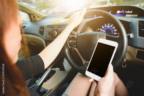 Mockup image of a woman holding and using mobile phone with blank screen while driver a car.