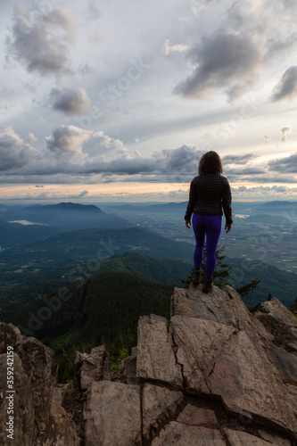 Adventurous Girl on top of a Rocky Mountain overlooking the beautiful Canadian Nature Landscape during a dramatic Sunset. Taken in Chilliwack, East of Vancouver, British Columbia, Canada.