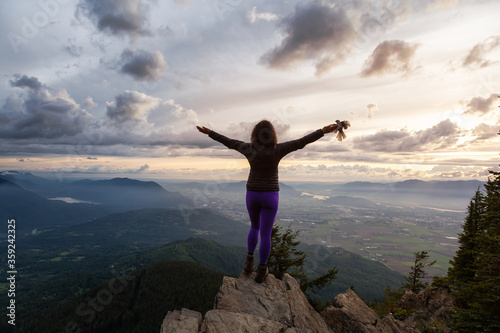 Adventurous Girl on top of a Rocky Mountain overlooking the beautiful Canadian Nature Landscape during a dramatic Sunset. Taken in Chilliwack, East of Vancouver, British Columbia, Canada. Bird on Hand © edb3_16