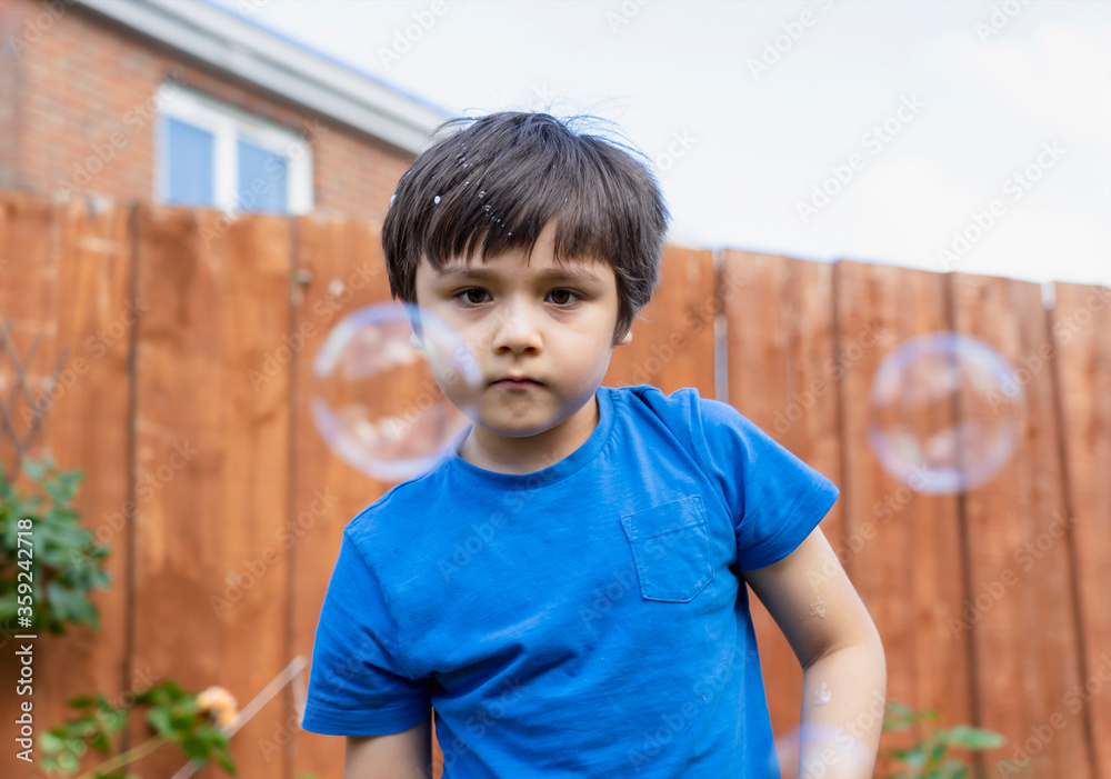Selective focus kid playing with soap bubbles in the garden, Active child boy playing outdoor in sunnyday summer. Positive children concept Selective focus kid playing with soap bubbles in the garden, Active child boy playing outdoor in sunnyday summer. Positive children concept