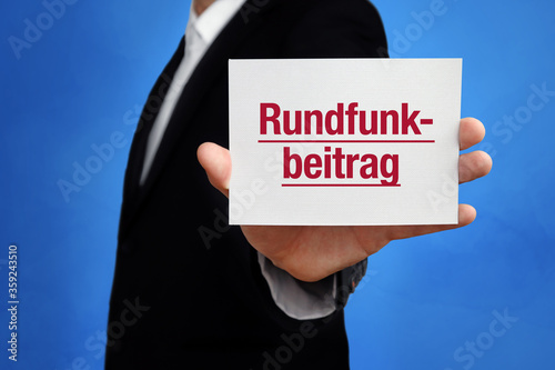 Rundfunkbeitrag. Geschäftsmann im Anzug hält Karte in die Kamera. Der Begriff Rundfunkbeitrag steht im Schild. Symbol für Business, Finanzen, Statistik, Analyse, Wirtschaft photo