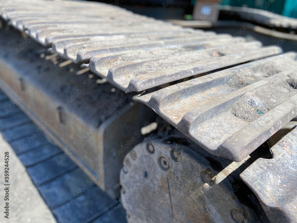 Main excavator undercarriage track chain and top carrier rollers and rails in dirt in close up Main excavator undercarriage track chain and top carrier rollers and rails in dirt in close up