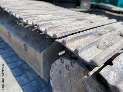 Main excavator undercarriage track chain and top carrier rollers and rails in dirt in close up