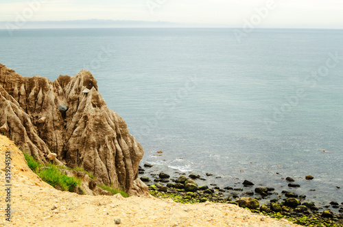 Clay cliff edge erosin at the wide open empty ocean shore line with mossy rocks photo