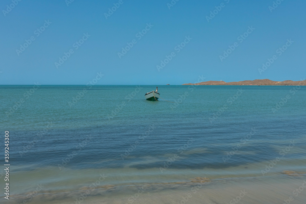 Lonely traditional Colombian fishing boat on sea water with clear water and blue sky - at Cabo de la vela, La guajira, Colombia Lonely traditional Colombian fishing boat on sea water with clear water and blue sky - at Cabo de la vela, La guajira, Colombia