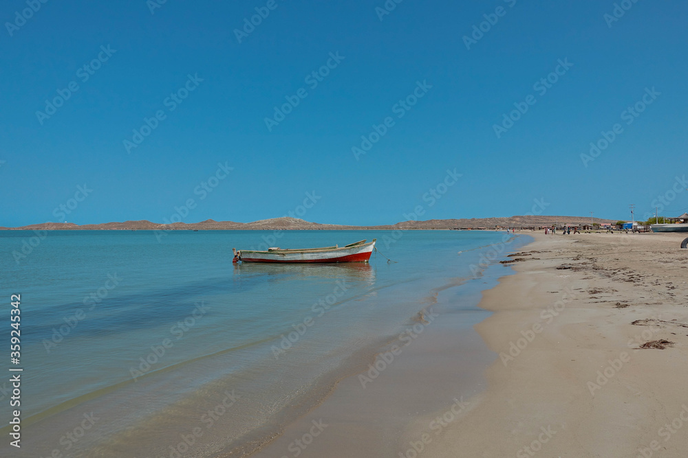 Lonely traditional Colombian fishing boat on sea water with clear water and blue sky - at Cabo de la vela, La guajira, Colombia Lonely traditional Colombian fishing boat on sea water with clear water and blue sky - at Cabo de la vela, La guajira, Colombia