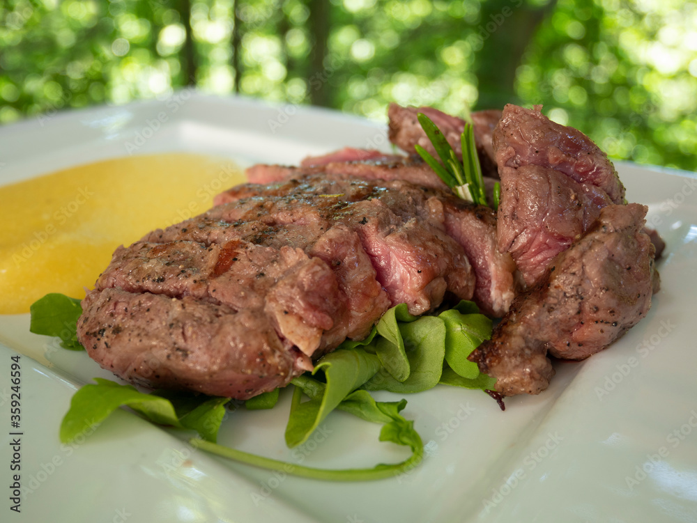 A plate of rare sliced beef with polenta. Undercooked meat. Tagliata di Manzo A plate of rare sliced beef with polenta. Undercooked meat. Tagliata di Manzo