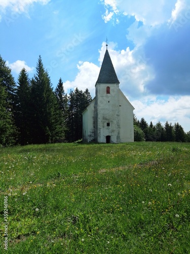 church on the Areh, Slovenia, green meadow with forest photo
