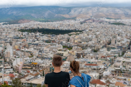 Young tourist Couple at the top of the mountain looking at the city of Athens, Greece. Bird eye drone style aerial shot.