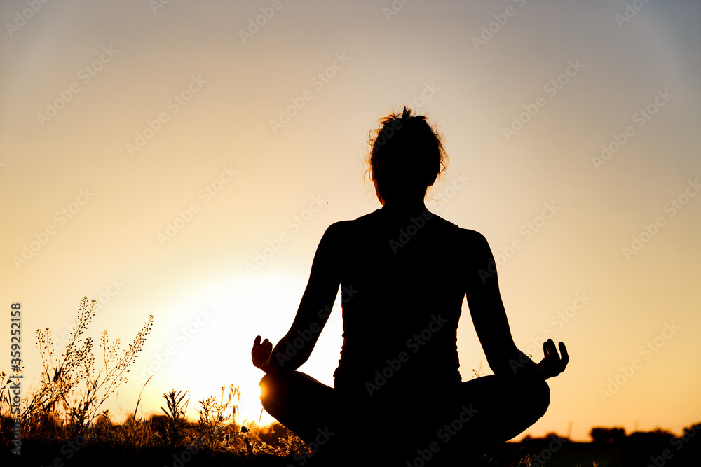 woman doing yoga at sunset in the field