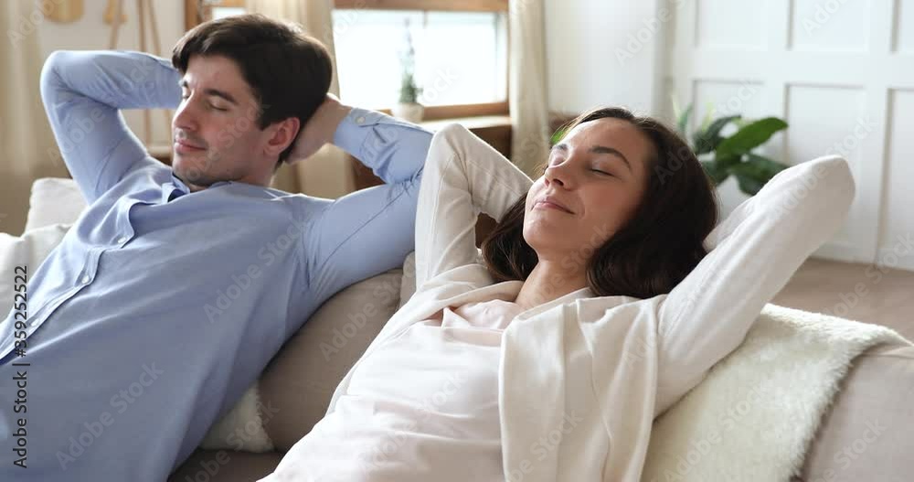 Peaceful calm young married couple leaning on comfortable sofa, enjoying sleepy lazy moment together in living room. Happy millennial family spouses relaxing on couch, meditating or daydreaming. Peaceful calm young married couple leaning on comfortable sofa, enjoying sleepy lazy moment together in living room. Happy millennial family spouses relaxing on couch, meditating or daydreaming.