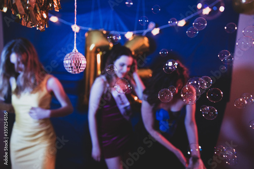 Group of three girls dancing and having fun at a birthday party with a disco ball