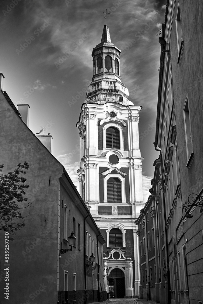 narrow street and belfry of the baroque church in Poznan, black and white. narrow street and belfry of the baroque church in Poznan, black and white.