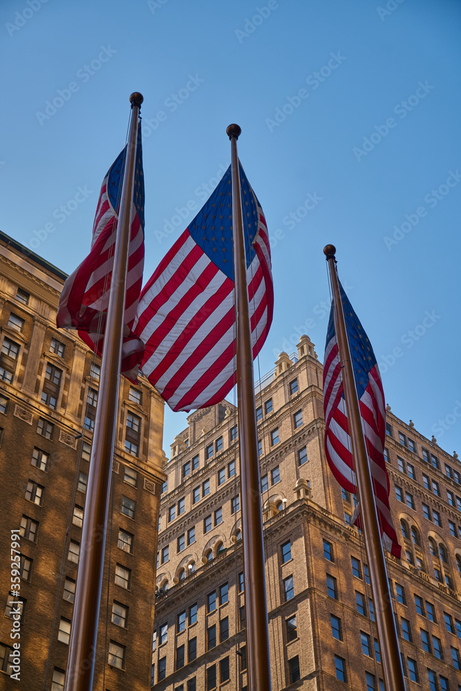 The American flag on the background of skyscrapers of New York city at the Manhattan, Times Square, USA at hot summer day