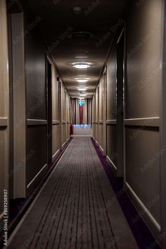 Long Tunnel hallway leading to exit sign hotel corridor 