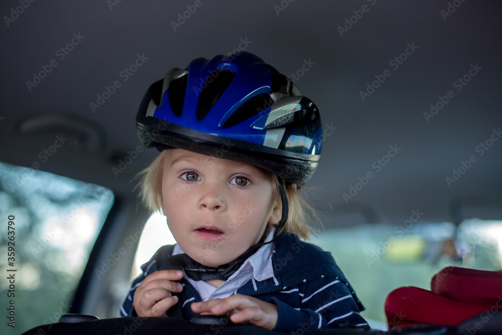 Child with helmet, riding in car after riding bike on summer evening Child with helmet, riding in car after riding bike on summer evening
