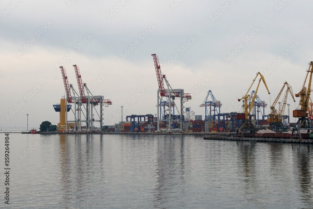 Containers in the port. Harbor cranes in cloudy weather.