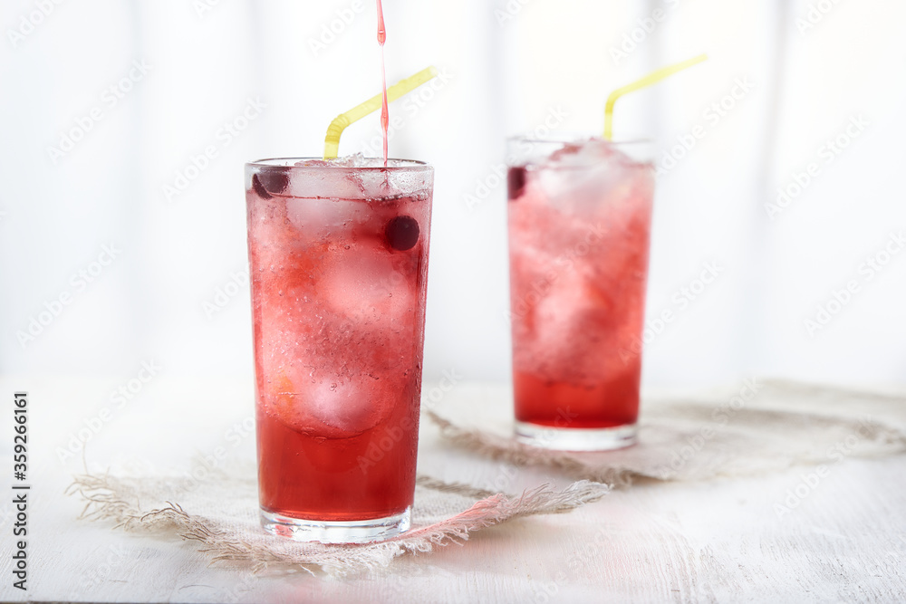 Two glasses of ice cold lemonade with blackcurrant berries . Pour the syrup into the glass. Two glasses of ice cold lemonade with blackcurrant berries . Pour the syrup into the glass.