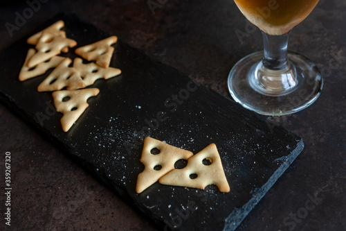 Glass of beer with salted crackers  on dark stone background