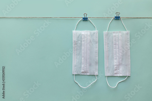 Medical masks hanging on a clothesline on green paper background. 