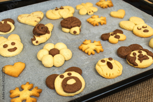 homemade cookies in the shape of dog, heart, elephant, butterfly, snowflake, slug, turtle, heart, rabbit, chamomile and owl in the tray. animal shaped cookies made for children.