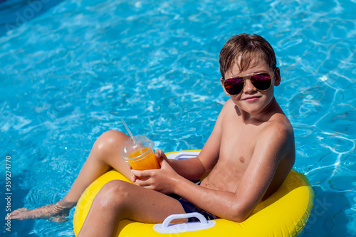 Kid boy holding juice in the swimming pool. Childhood, summer and vacation concept