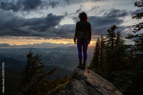 Adventurous Girl on top of a Rocky Mountain overlooking the beautiful Canadian Nature Landscape during a dramatic Sunset. Taken in Chilliwack, East of Vancouver, British Columbia, Canada. © edb3_16