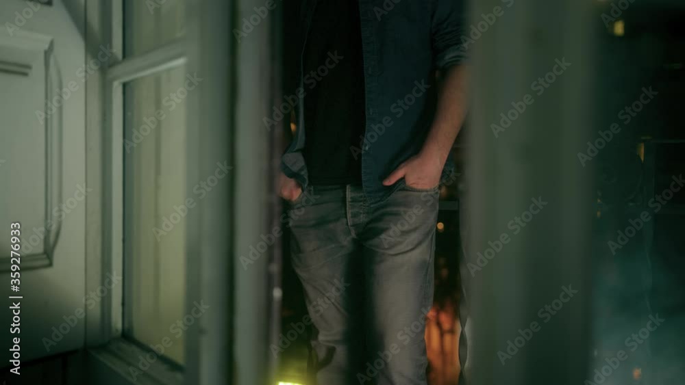 Unrecognizable man stands on window balcony grabs mobile from pocket and read message with a 5G connectivity network at night medium shot Unrecognizable man stands on window balcony grabs mobile from pocket and read message with a 5G connectivity network at night medium shot