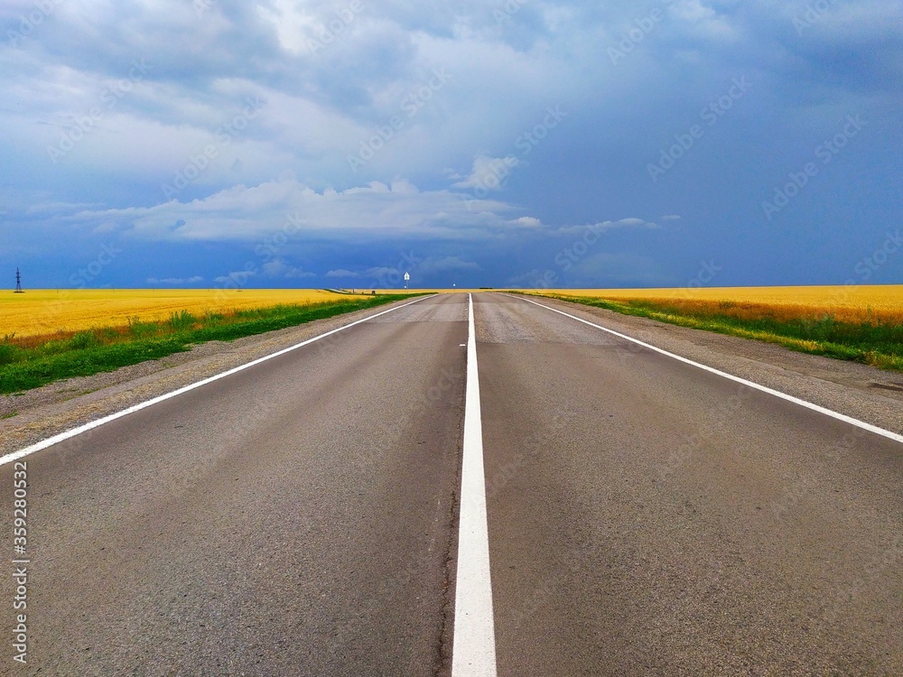 paved road with white markings going into the distance and past fields paved road with white markings going into the distance and past fields